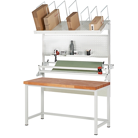 Table d'emballage avec étagères, boîtes en carton, rouleau de papier et plan de travail en bois. La table a un cadre blanc et un mur perforé.