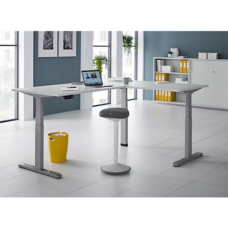 Bureau d'angle avec ordinateur portable, chaise de bureau et poubelle jaune.