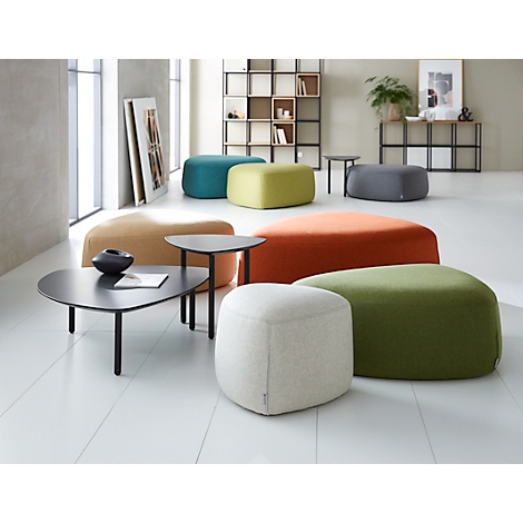 Diverses assises et tables colorées dans une pièce lumineuse. Certaines sont rondes et d'autres carrées, de différentes couleurs.