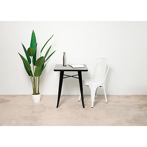 Scène : table, chaise et plante devant un mur blanc. Sur la table : bouteille et carnet. La scène est minimaliste et moderne.