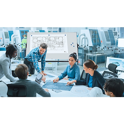 Plusieurs personnes discutent de plans sur une table, dont un homme pointant les plans.