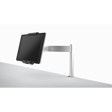 A silver tablet holder with a tablet against a white background. The tablet is black, and the holder is attached to the wall.