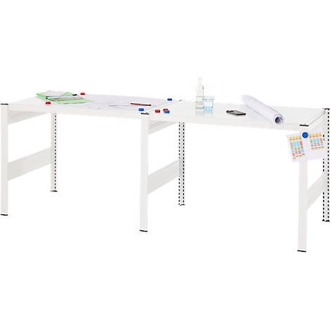 Longue table blanche avec du papier, des stylos et des bouteilles dessus. Un mémo est accroché sur un pied de table.