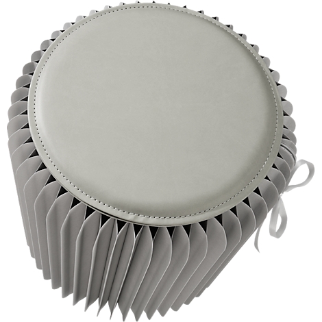 Tabouret rond gris clair avec côtés plissés et couvercle crème. Un ruban est attaché en haut pour l'attacher.