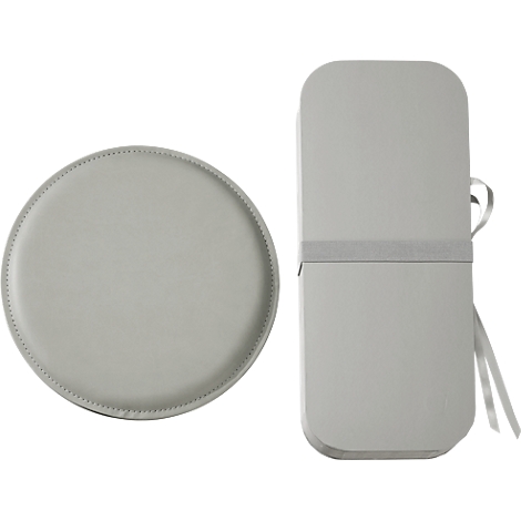 Plateau rond gris clair à côté d'une boîte oblongue. Le plateau a une couture décorative, la boîte un ruban gris.