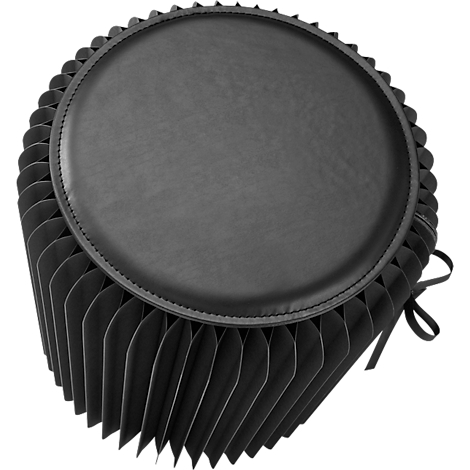 Tabouret noir avec assise ronde et rembourrée. Les côtés sont faits d'éléments pliés. Un ruban orne le côté.