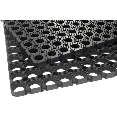 Vue détaillée d'un tapis en caoutchouc noir avec des trous et de petits picots pour l'antidérapance. Un autre tapis est posé dessus.