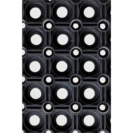 Gros plan d'un tapis en caoutchouc noir avec un motif régulier de grands et petits trous circulaires.