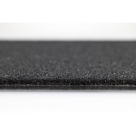 Gros plan sur un tapis en caoutchouc noir texturé ou un revêtement de sol à surface granuleuse.