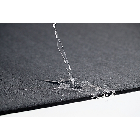 De l'eau est versée sur un tissu noir texturé. Le tissu repousse l'eau. Le fond est blanc.