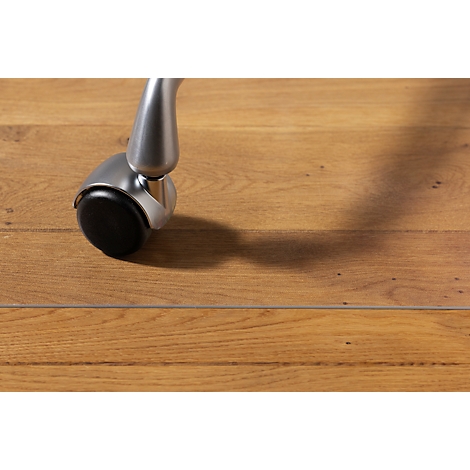 Gros plan d'une roulette de chaise argentée avec une roue noire sur un plancher en bois clair, projetant une ombre.