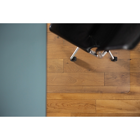 Vue de dessus d'une chaise de bureau sur un plancher en bois, un mur bleu à gauche.
