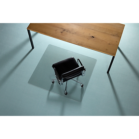 Chaise de bureau sur un tapis de sol transparent sous une table en bois avec pieds noirs.