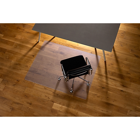 Chaise de bureau sur tapis de bureau, devant la table, sur plancher en bois, vue plongeante.