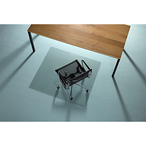 Chaise de bureau sur tapis de sol transparent sous une table en bois. La chaise est sur un sol bleu.