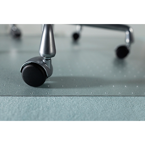 Gros plan d'une roulette de chaise avec une roue noire et un support argenté. La surface est un tapis de protection transparent.