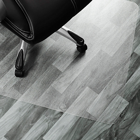 Chaise de bureau avec tapis. La chaise est posée sur un tapis de protection de sol transparent, posé sur un plancher en bois.