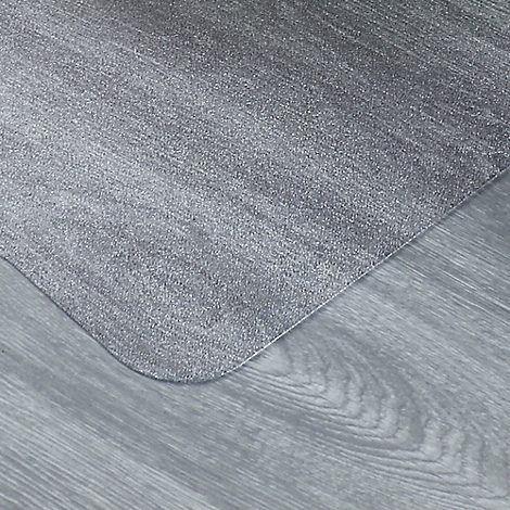 Tapis gris posé sur un plancher en bois gris. Le coin arrondi du tapis repose sur le plancher en bois.