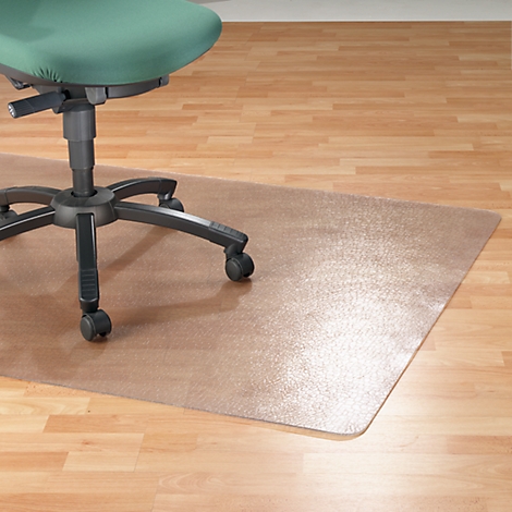 Une chaise de bureau est posée sur un tapis de sol transparent sur un parquet clair.