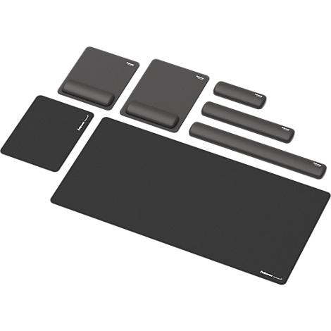 Un homme est assis à un bureau réglable en hauteur, souriant. Il a une main sur la souris et ses pieds sur un repose-pieds. Un moniteur est sur la table.