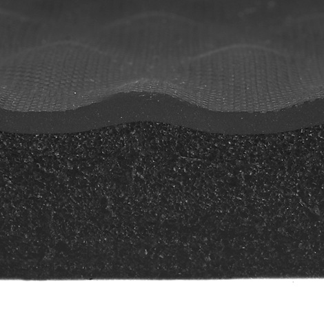 Gros plan sur de la mousse noire avec des structures ondulées et une couche de tissu texturé.