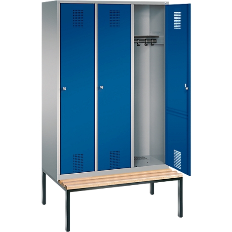 Un armario con puertas azules, una puerta abierta, un banco de madera.