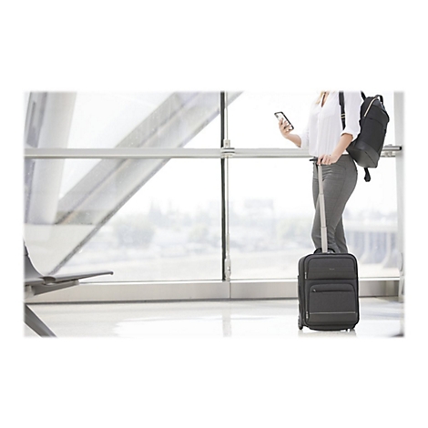 Frau im Flughafen mit Koffer und Smartphone. Sie trÃ¤gt einen Rucksack.