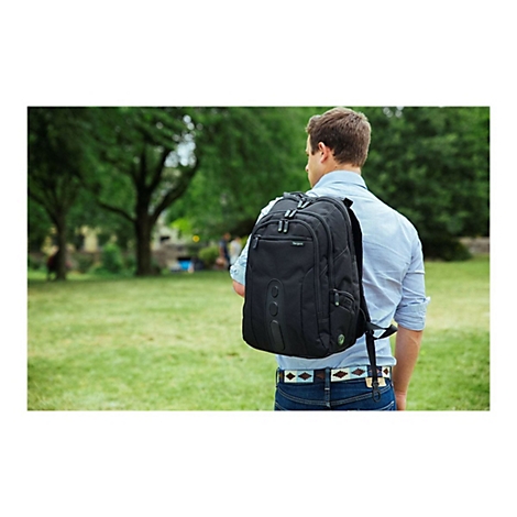 Ein Mann, der einen schwarzen Rucksack auf dem Rücken trägt, geht durch einen Park. Der Rucksack hat das Logo 'Targus'.