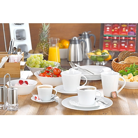 Buffet de petit-déjeuner riche : café, fruits, jus, pâtisseries et sélection de pains. Disposé sur une table en bois.