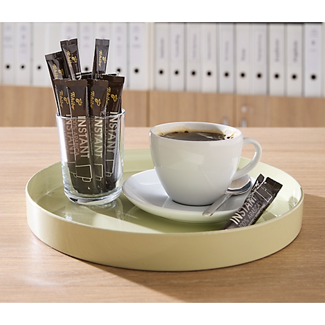 Ein hellgrünes Tablett mit einer Kaffeetasse und einem Glas voller Instant-Kaffeesticks in einem Büro.