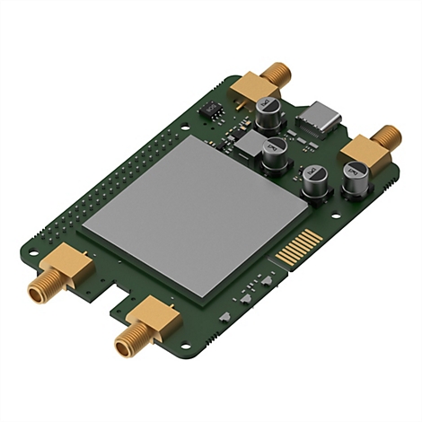 Eine grüne Platine mit elektronischen Komponenten, Schraubanschlüssen und einem großen grauen Chip. Auf weißem Hintergrund.