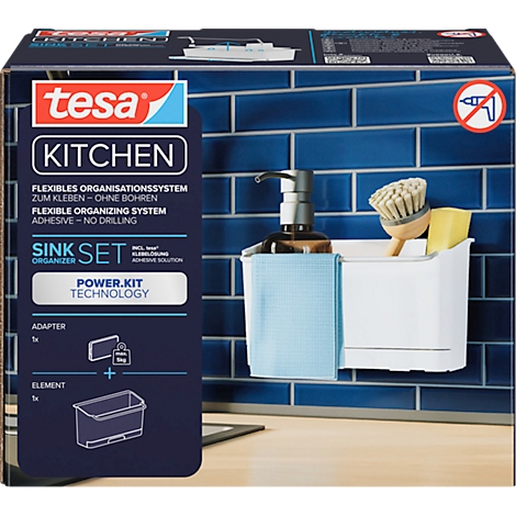 Système d'organisation de cuisine avec ensemble évier, distributeur de savon, brosse, éponge et chiffon de nettoyage. Le fond montre des carreaux bleus.