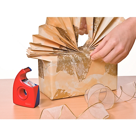 Gift being wrapped with brown paper and a ribbon. Hands hold the gift.
