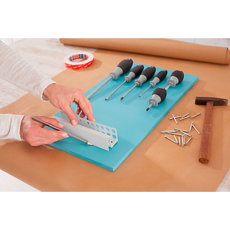 Hands holding angle and pencil on turquoise board with tools. Screwdrivers, hammer and nails are ready.