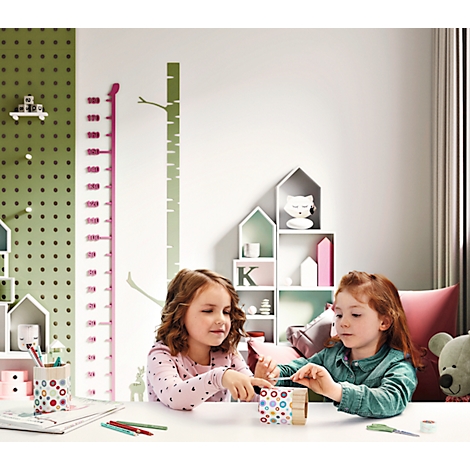 Two girls crafting together at a table. A green height chart tree is depicted on the wall.
