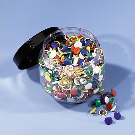 An open jar of colorful thumbtacks. Some lie beside.