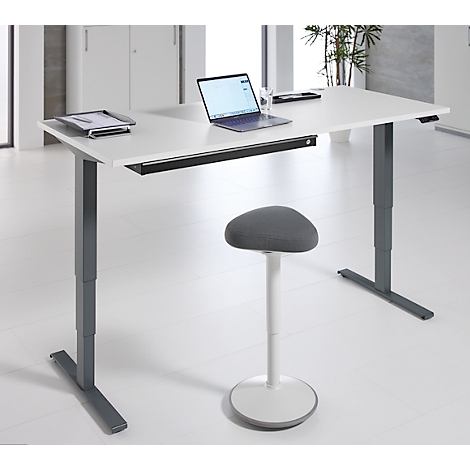 Bureau blanc réglable en hauteur avec ordinateur portable et tabouret debout sur fond clair.