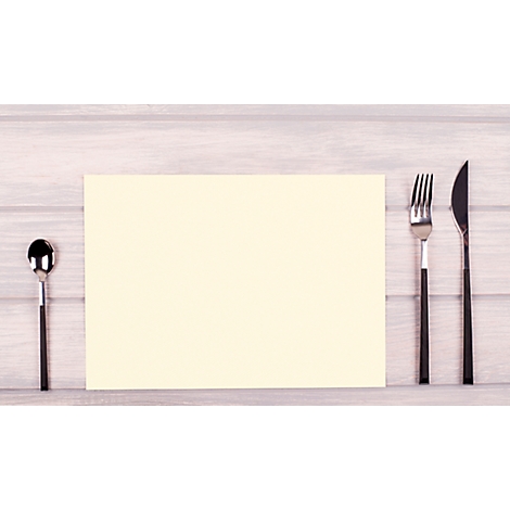 Gedeck mit leerem Blatt Papier, Löffel links, Messer und Gabel rechts auf hellem Holz.