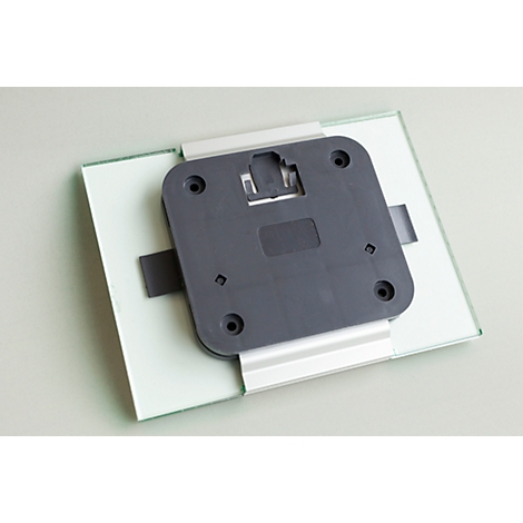 Gray bracket with black plastic plate on glass plate. Holes are attached at the corners.
