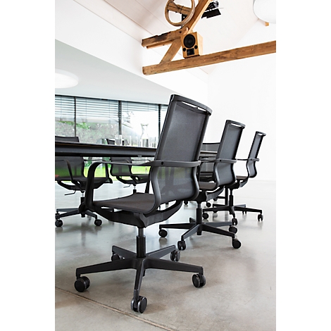 Plusieurs chaises de bureau noires à dossier en filet disposées autour d'une longue table de conférence dans un espace moderne.
