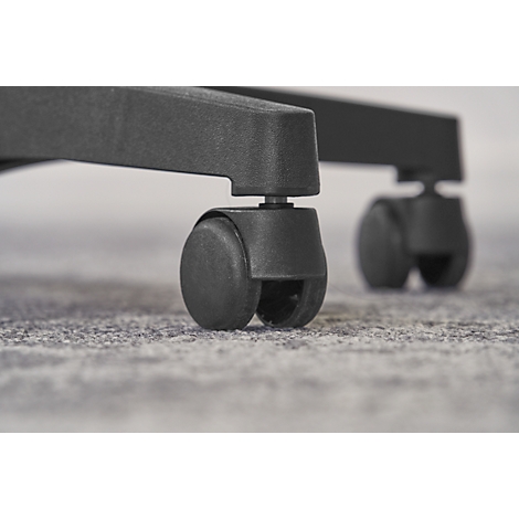 Close-up of two black chair wheels on an office chair standing on a textured, gray floor.