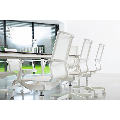 White office chairs around a table with glasses and a carafe, bright room, large windows.