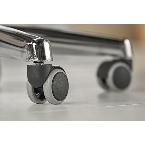 Close-up of an office chair caster with two wheels, gray rim, and chrome frame on a light floor.