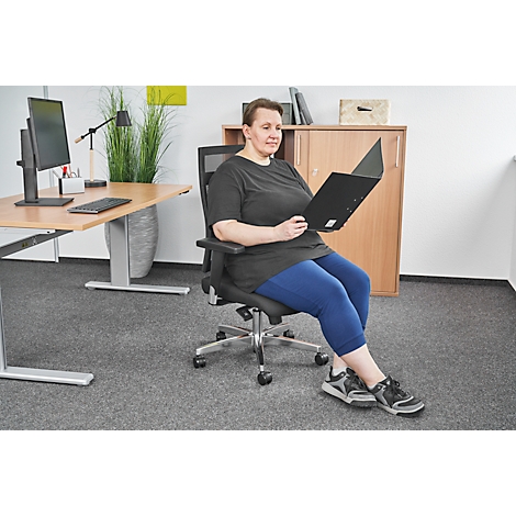 Woman reading documents while sitting in an office chair; background: desk, cabinet.