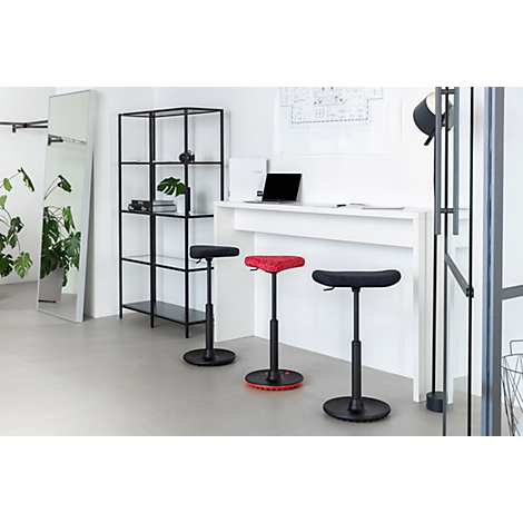 Three standing stools in an office. A black one, a red one, and another black stool stand in front of a white counter. A mirror and a shelf are also visible.