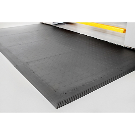 Black rubber mat, textured with round studs. Several mats stacked on top of each other.