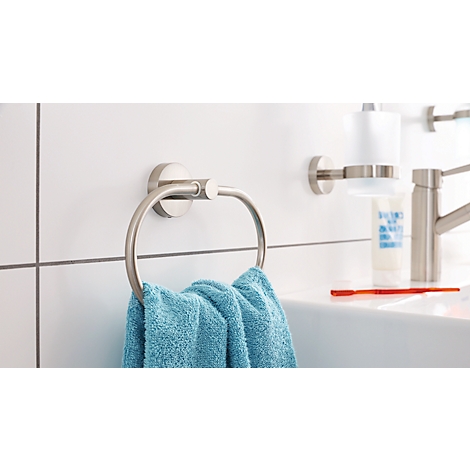 Metal towel ring with blue towel, next to a sink with soap dispenser and faucet.