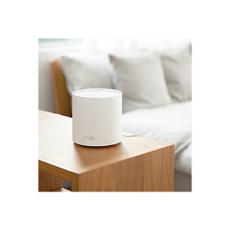 Routeur cylindrique blanc sur une table en bois, un lit en arrière-plan. Le routeur dit « deco ».