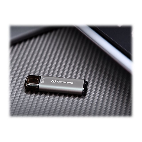 ClÃ© USB argentÃ©e avec logo 'Transcend' et impression 25 Go, posÃ©e sur une surface texturÃ©e.
