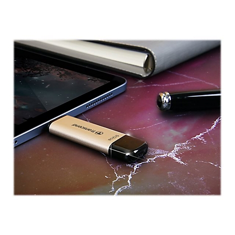 ClÃ© USB dorÃ©e Ã  cÃ´tÃ© d'une tablette, d'un stylo et d'un bloc-notes sur une surface en marbre. Vue rapprochÃ©e.